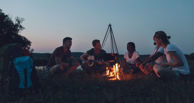 Mennesker med gitar rundt et bål